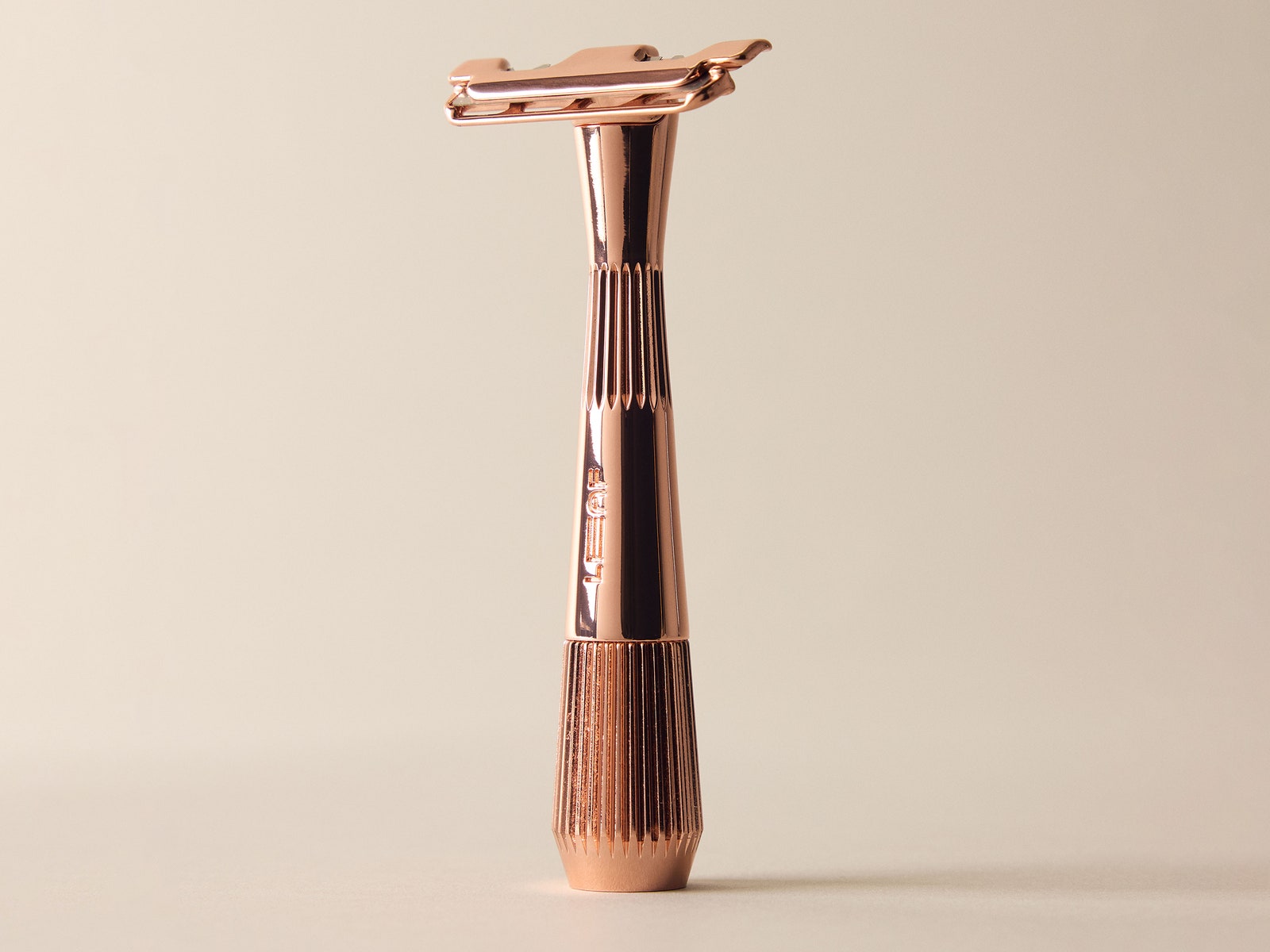 Leaf Thorn a rose gold colored handheld razor on a beige background